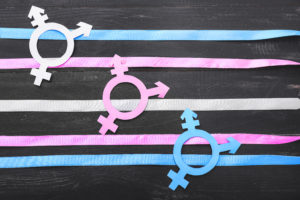 Symbols of transgender pride with ribbons on dark wooden background. We are proud to provide gender therapy in Illinois.