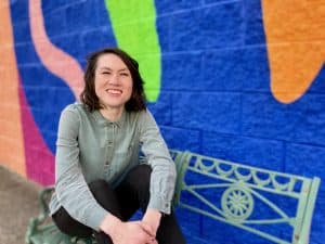 Photograph of Miranda Nadeau, Ph.D. sitting on a bench