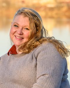 Photograph of Kalila Beehler, Ph.D. smiling at the camera, with a fuzzy winter scene in the background